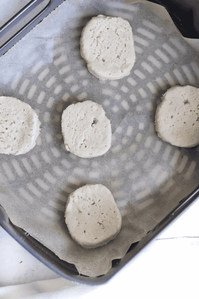 Scooping 2 tablespoons of cookie dough onto parchment paper in air fryer.