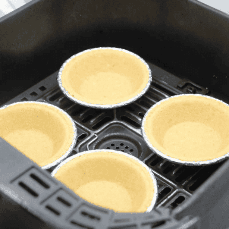 Placing pie crusts in air fryer basket and lightly pre-cooking at 300&deg;F