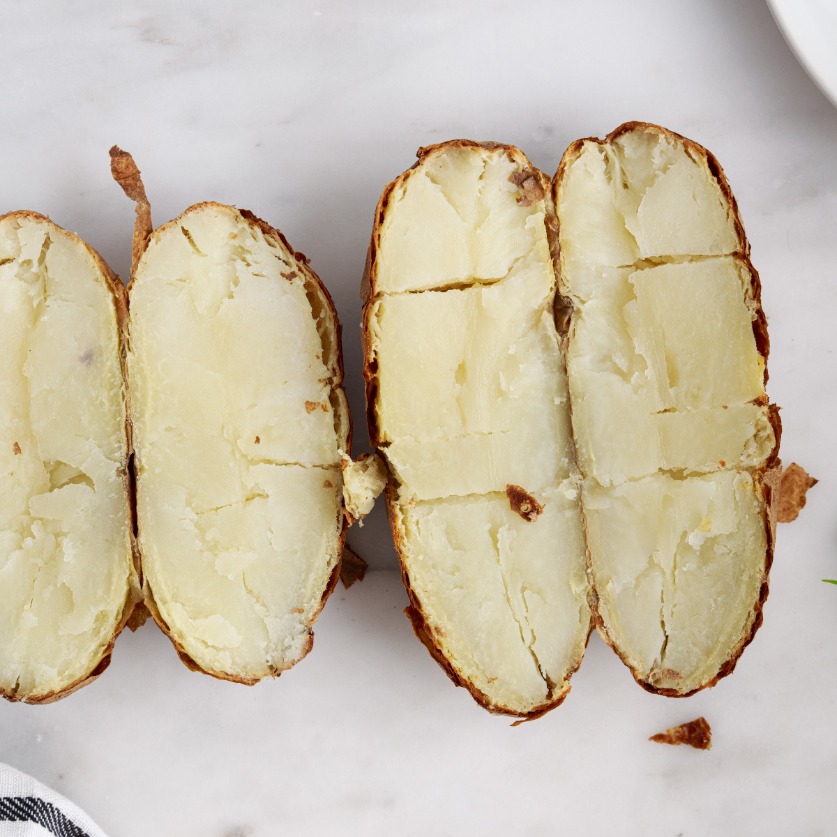 Air fried potatoes cooled briefly then peeled or scooped with spoon to separate soft fluffy interior from skins before mashing.