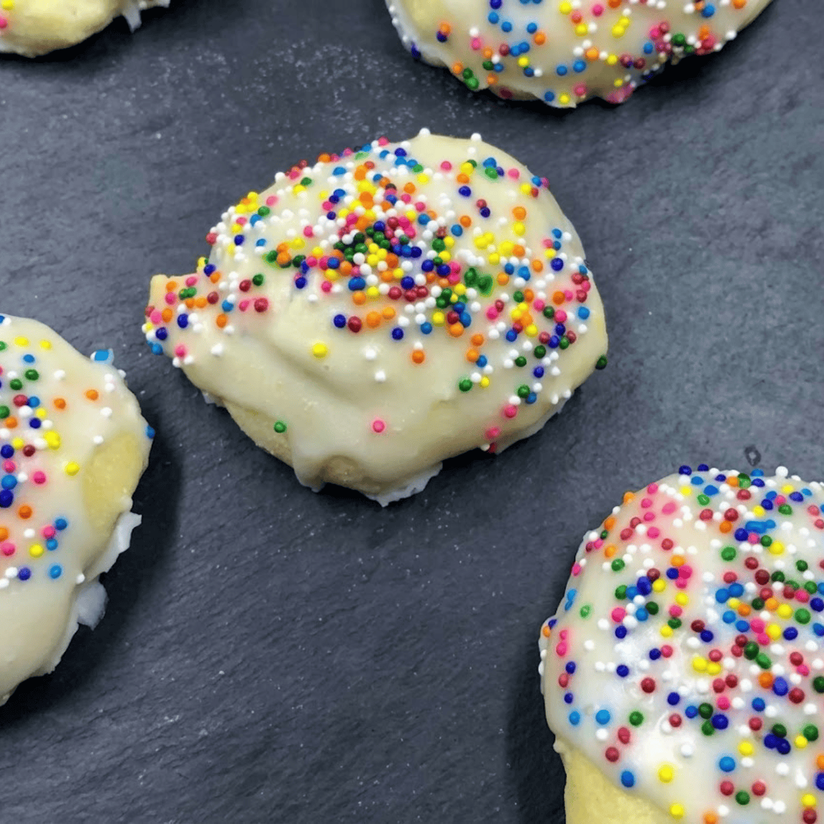 Dipping Italian cookies into powdered sugar glaze and topping with colorful sprinkles.