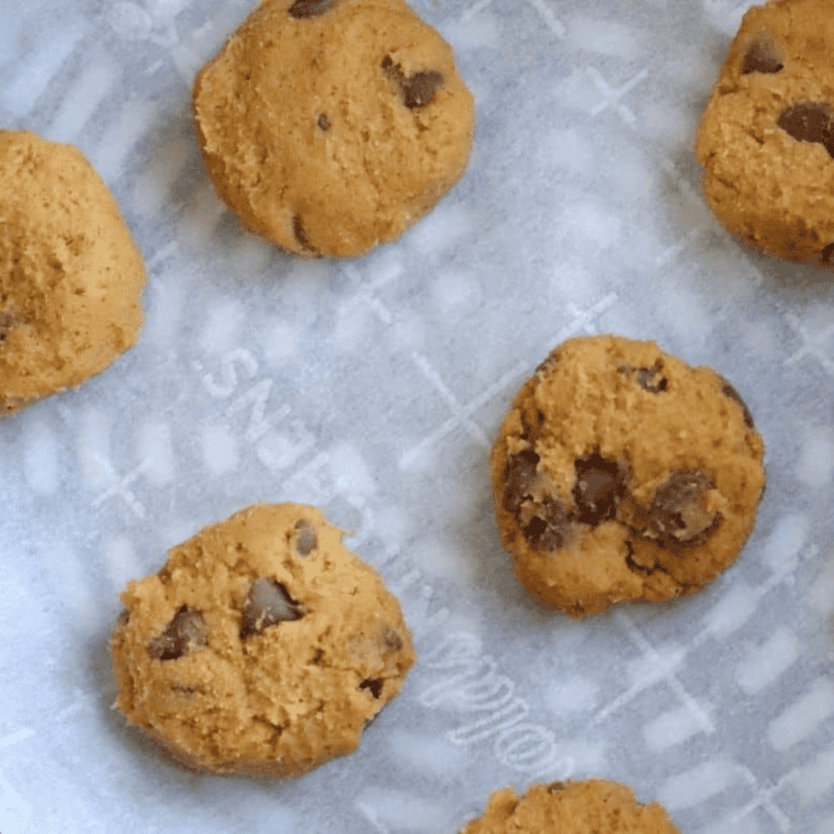 Peanut butter cookie dough being mixed with flour, eggs, and vanilla in a bowl.