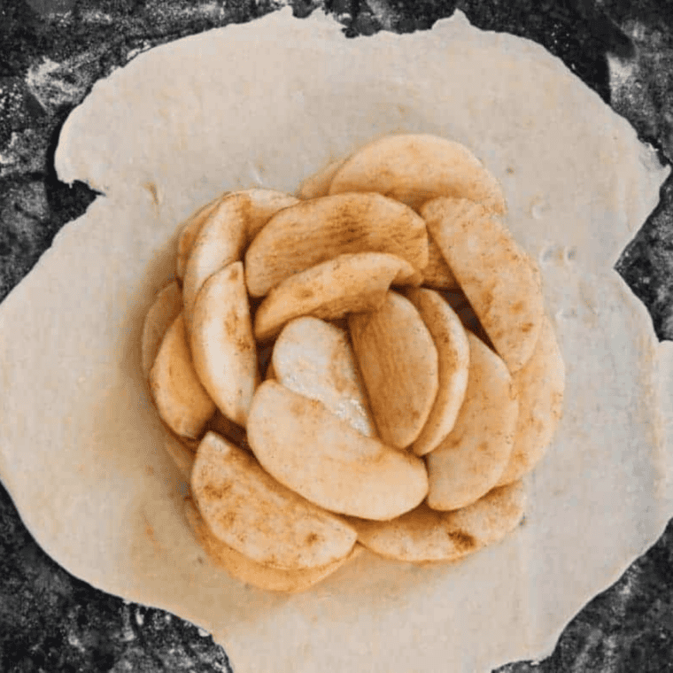 Sliced apples tossed with brown sugar, cinnamon, and lemon juice in a bowl