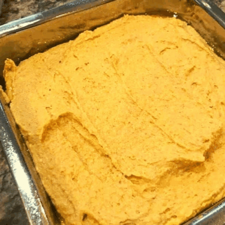 Pumpkin cornbread batter poured into a pan, smoothed with a spatula, ready to cook in the air fryer at 320°F.