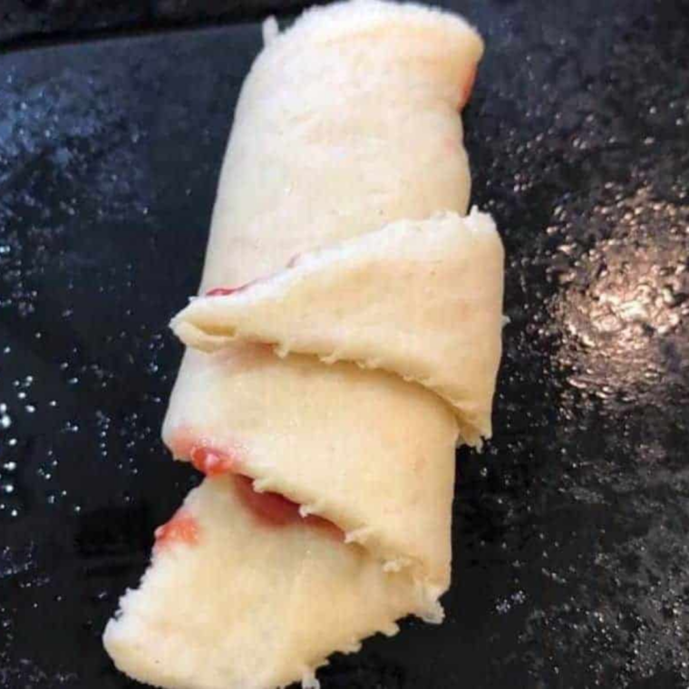Filled crescent rolls arranged in an air fryer basket, ready to cook at 320&deg;F.