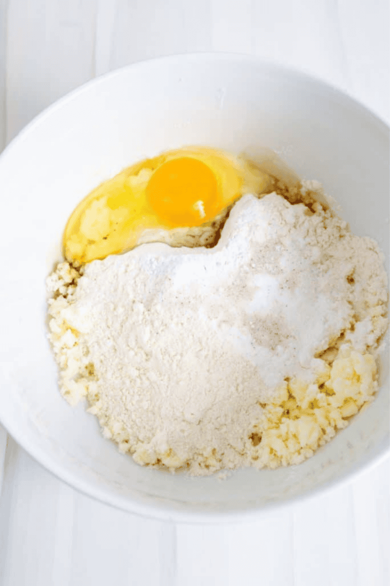 Mixing creamed butter and sugar with dry ingredients, egg, and vanilla to form confetti cookie dough.
