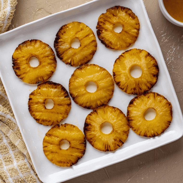 Caramelized honey glazed pineapple served warm on a plate, ready to eat.