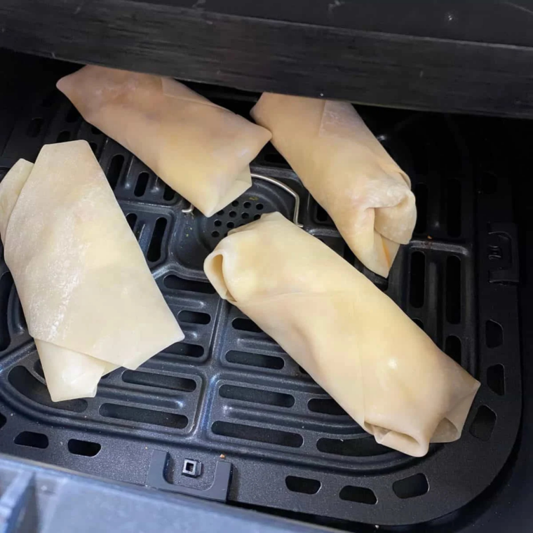 Blueberry egg rolls placed seam side down in an air fryer basket