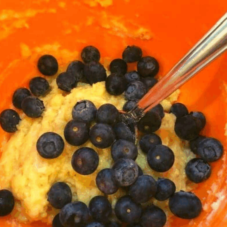 Gently folding fresh or frozen blueberries into muffin batter