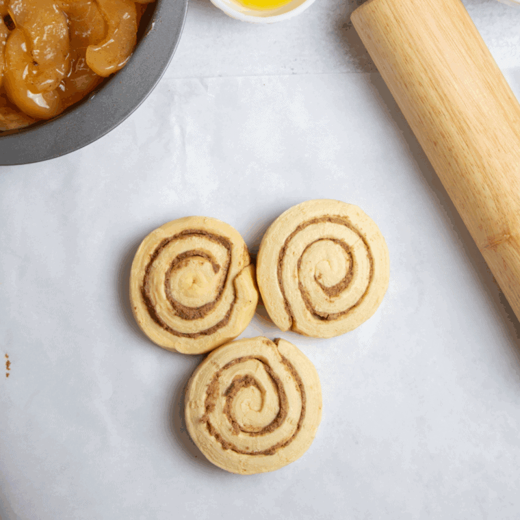 Pressing cinnamon rolls into a greased air fryer pan to form the crust and brushing with melted butter