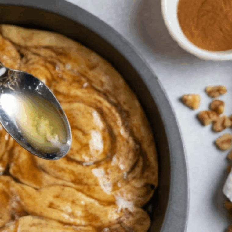 Rolling and sealing cinnamon roll dough over apple filling, brushing with butter, and baking in air fryer until golden brown