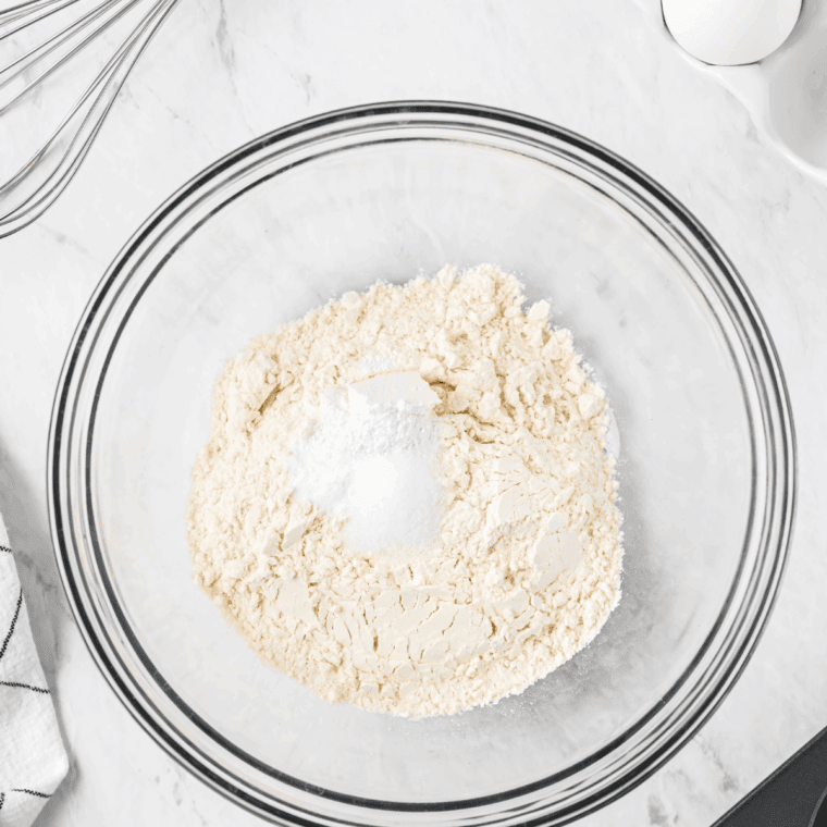 Mixing sugar, lemon zest, lemon juice, flour, baking powder, baking soda, and salt in a small bowl for muffin batter