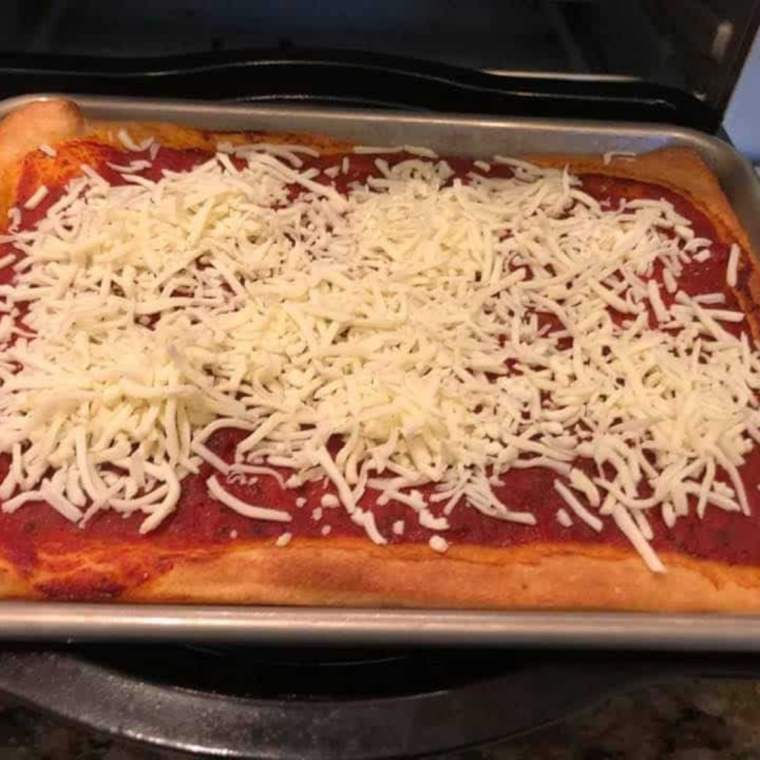 Par-baked crust topped with freshly shredded mozzarella, ready for the second air fry