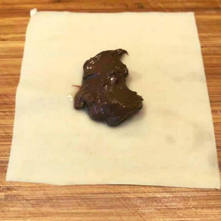 A rounded teaspoon of Nutella spooned into the center of a single wonton wrapper