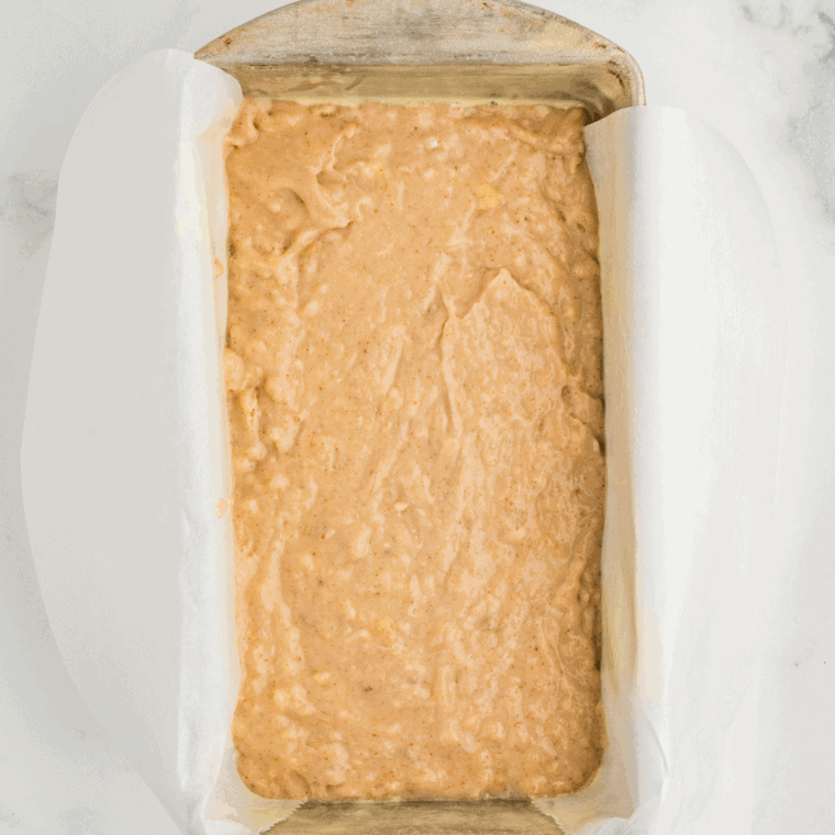 Pouring banana bread batter into a greased loaf pan, smoothing the top, and baking until golden brown and cooked through.