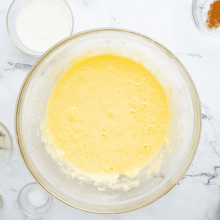 Whisking almond butter, honey, lemon juice, lemon zest, and vanilla extract together until smooth for lemon protein bar mixture.