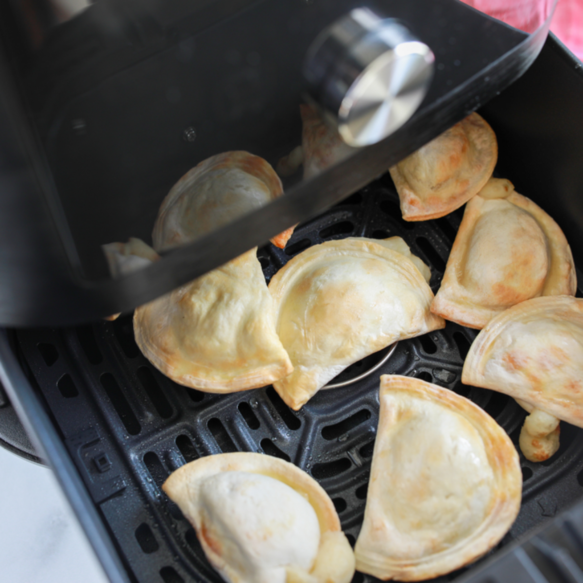 closeup: cooked frozen pierogies in air fryer basket