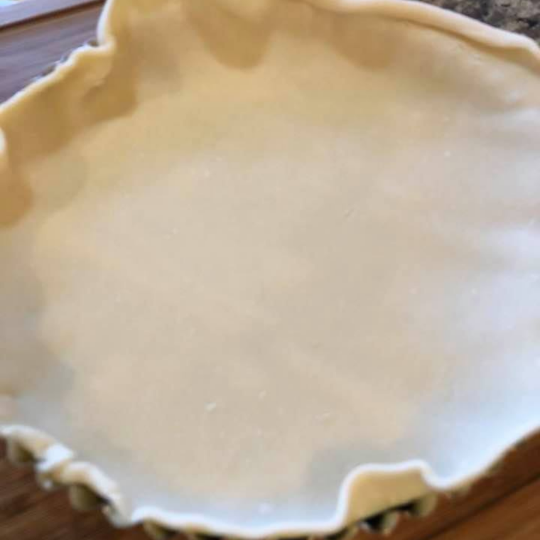 Refrigerated pie crust pressed into a round tart pan with excess dough draped over the rim