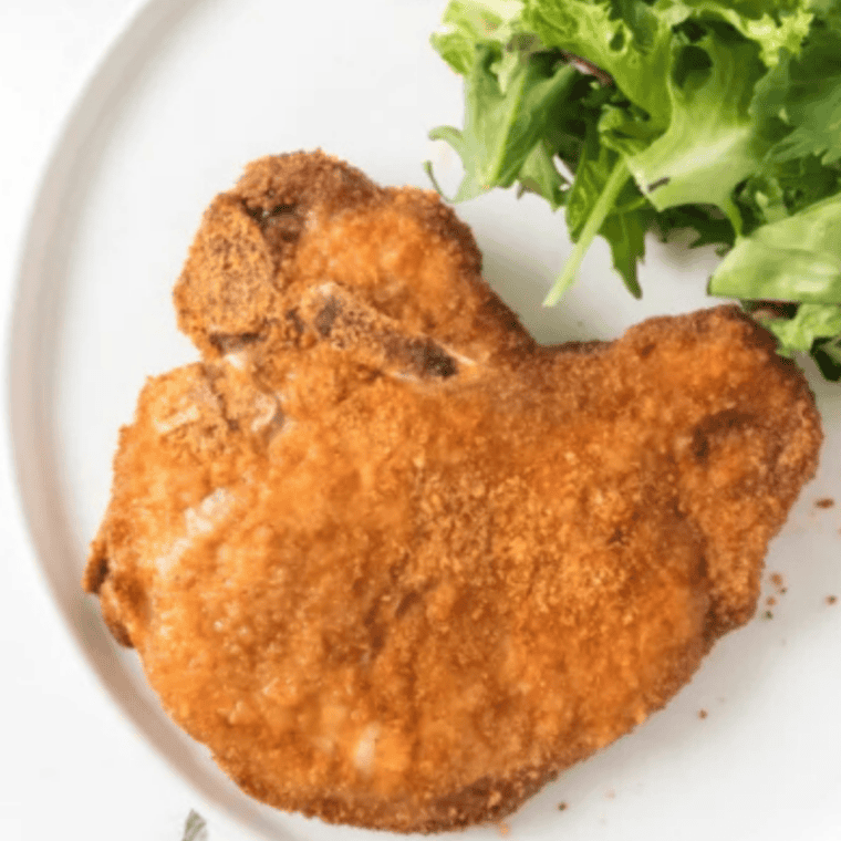 Golden brown pork chops coated with Shake and Bake seasoning in an air fryer