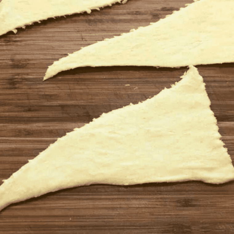 Crescent roll dough separated into triangles on a cutting board