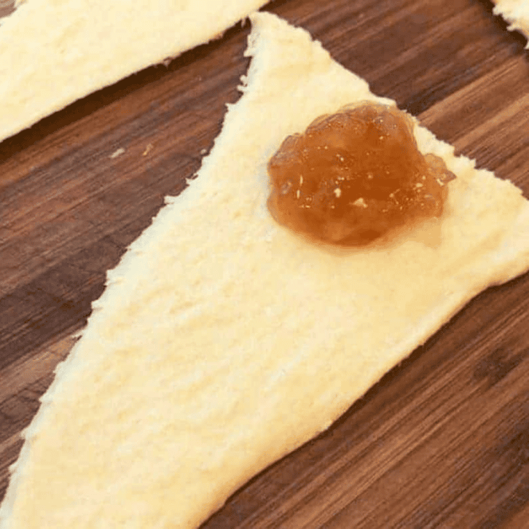 Spoonful of cinnamon apple filling on the wide end of a crescent triangle