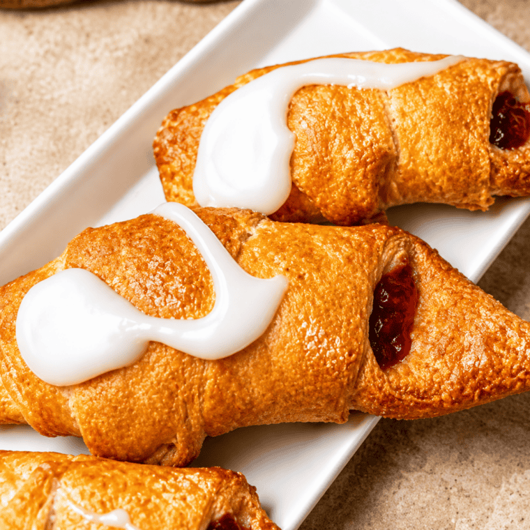 Golden cherry filled crescents drizzled with vanilla glaze on a plate