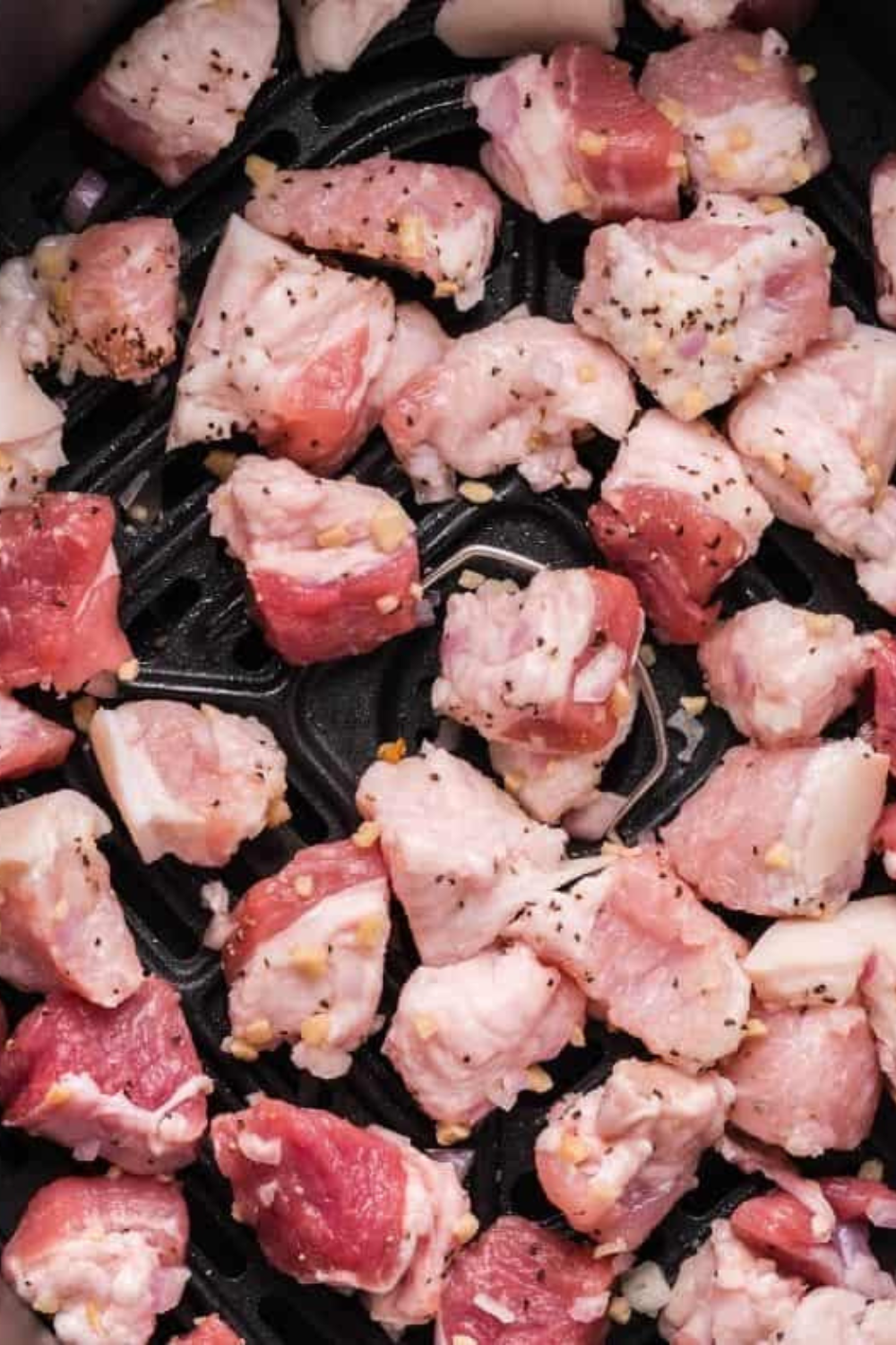 Raw pork belly pieces coated with salt and black pepper in a mixing bowl before cooking.
