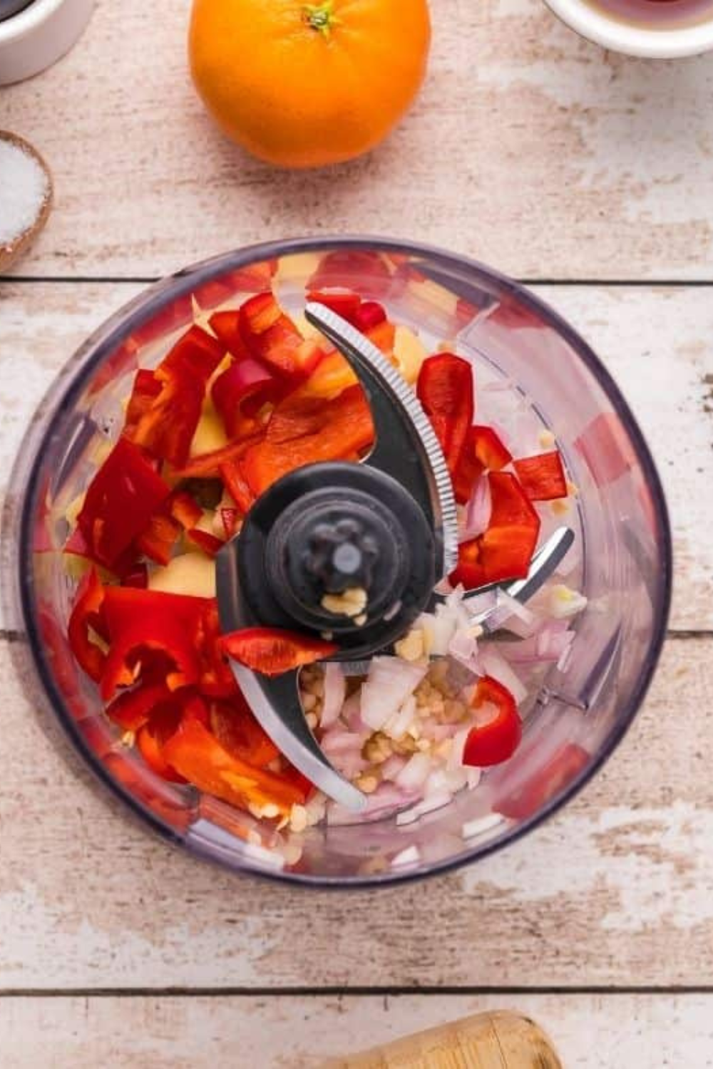 Crispy pork belly cooking in an air fryer basket while spicy ginger sauce simmers in a saucepan after blending fresh ginger, garlic, chili peppers, mandarin orange, soy sauce, and maple syrup.