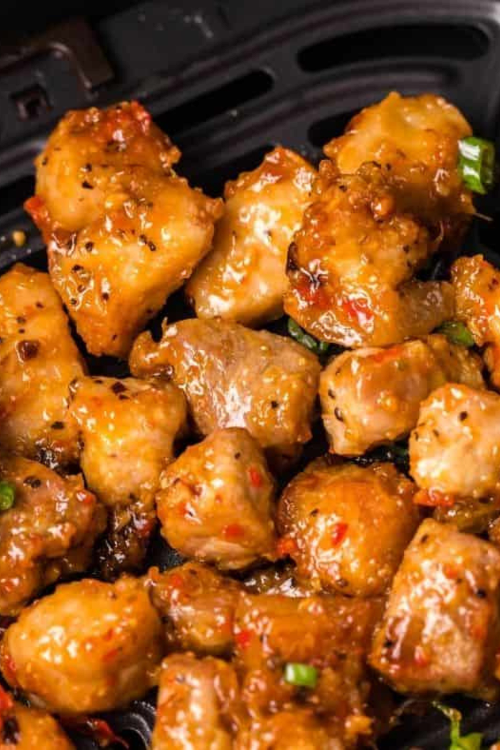 Crispy air-fried pork belly tossed in spicy ginger sauce in a mixing bowl and garnished with fresh green onions, ready to serve hot.