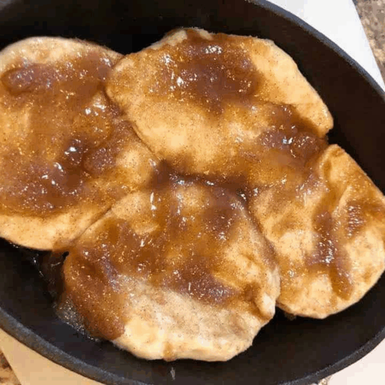 Biscuits fully coated in butter, brown sugar, and cinnamon, arranged in baking pan