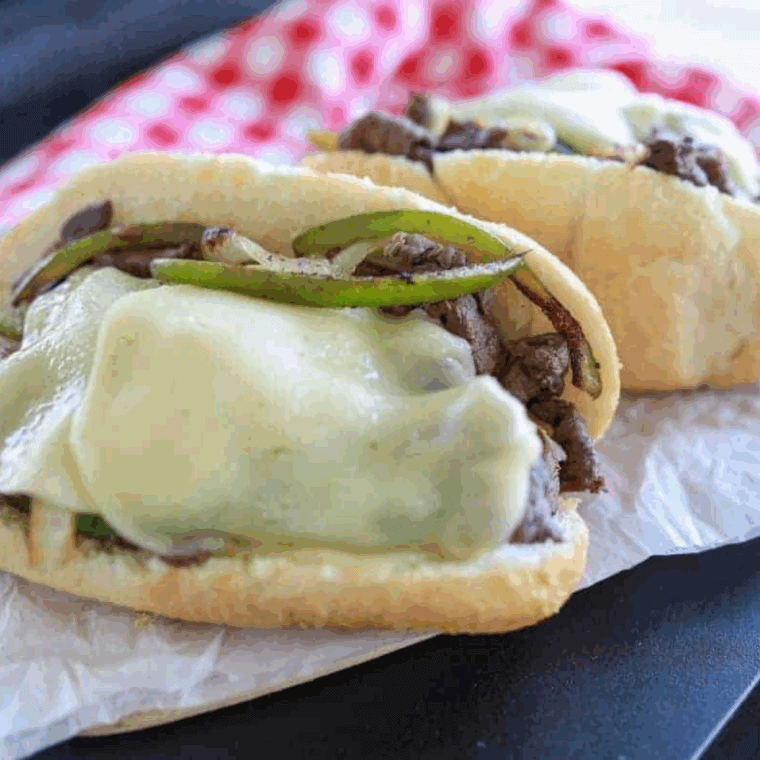 Easy Ninja Foodi Philly Cheesesteaks with shaved steak, peppers, onions, and melted cheese in a hoagie roll.