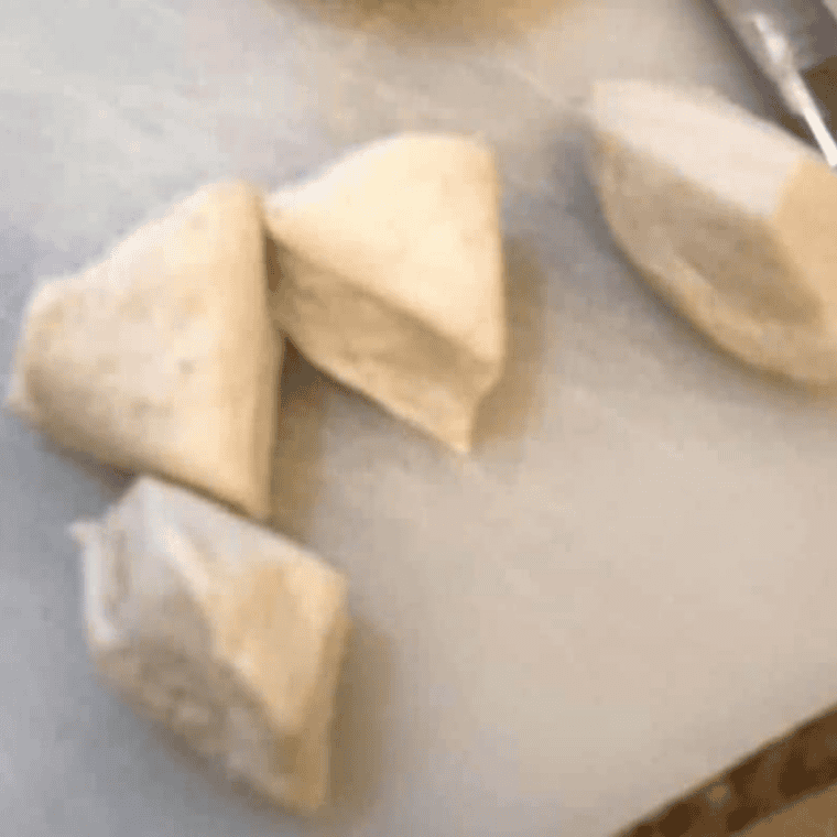 Refrigerated biscuits cut into quarters on a cutting board