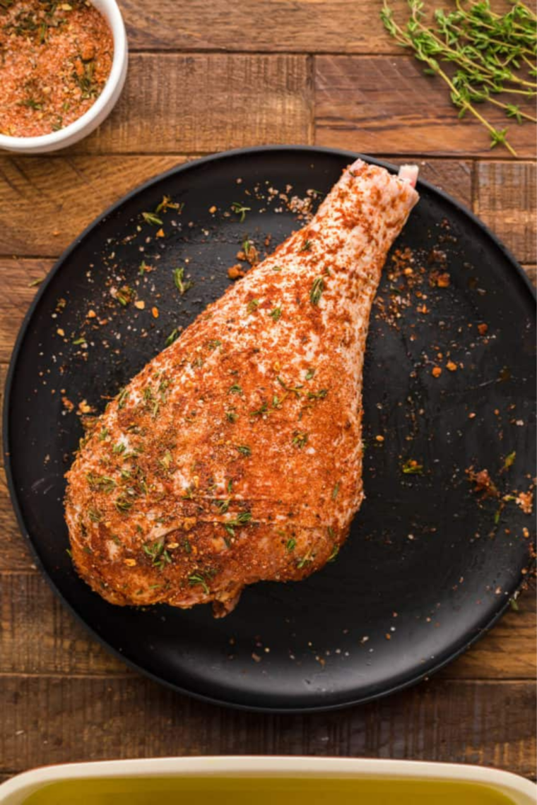 Rubbing Cajun seasoning onto raw turkey legs before air frying