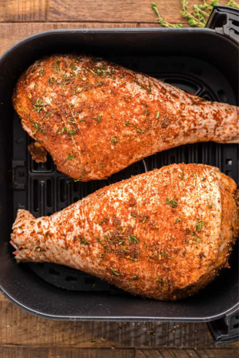Seasoned turkey legs in a single layer in the air fryer basket
