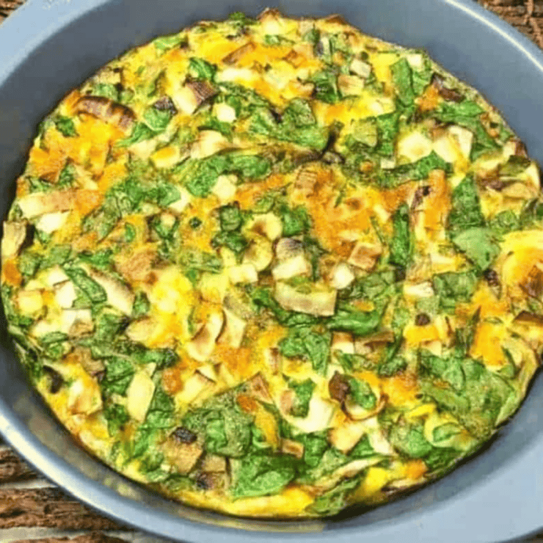 Roasted vegetable frittata sliced on a plate showing fluffy eggs with colorful vegetables baked inside.