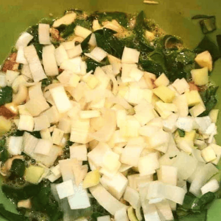 Eggs being cracked into a mixing bowl with assorted vegetables added for a roasted vegetable frittata mixture.
