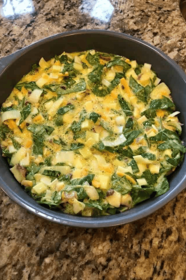 Egg mixture with cheese being poured into a greased baking dish for a roasted vegetable frittata before baking.