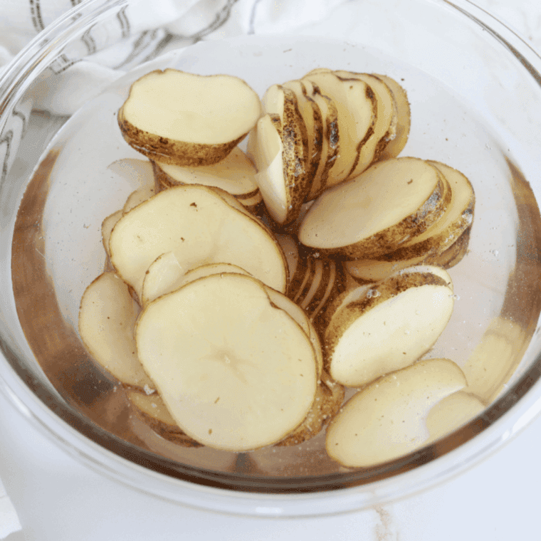 Sliced potatoes soaking in a large bowl of cold water for 20 minutes
