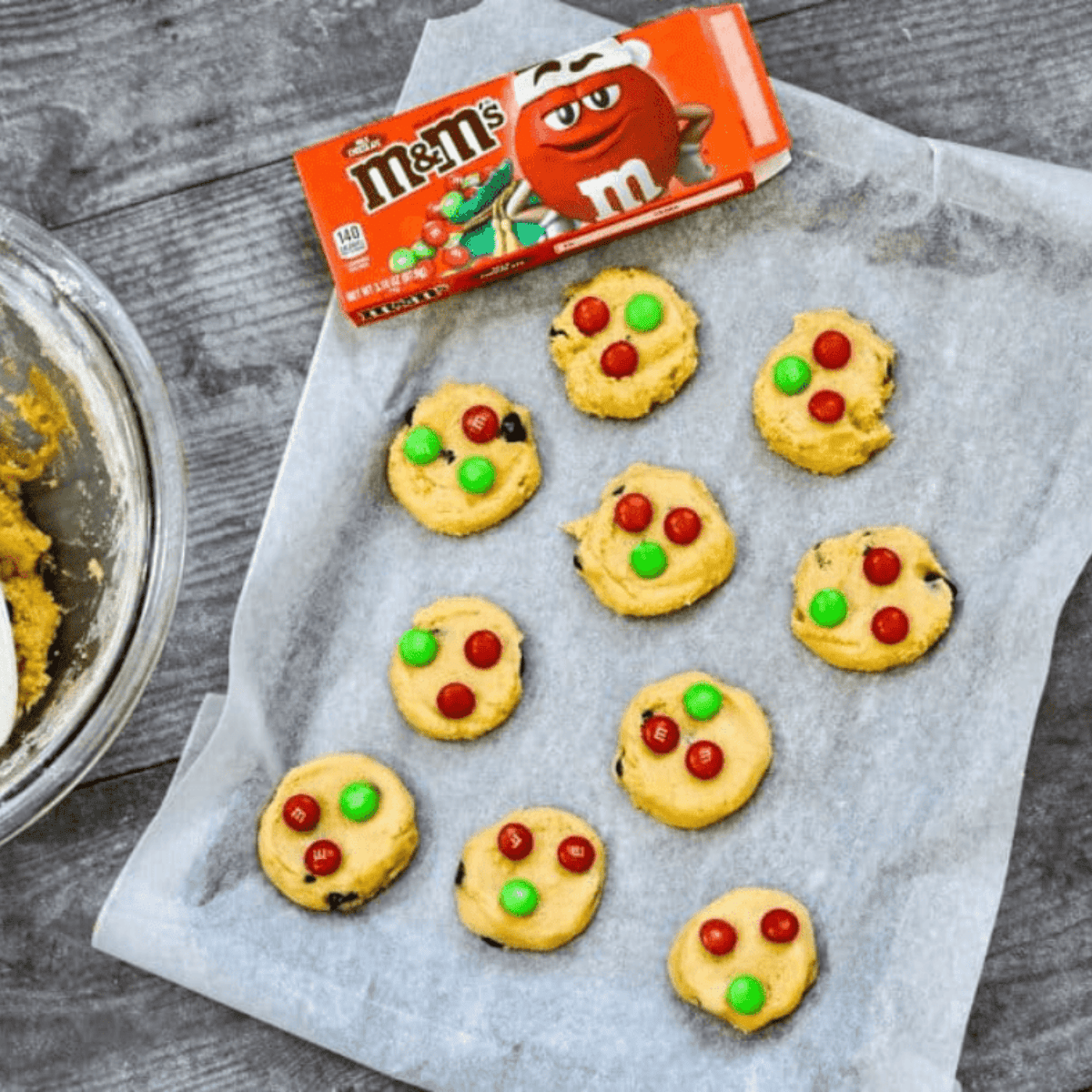 cookie dough scooped onto parchment paper in air fryer basket with cookies baking until golden edges form