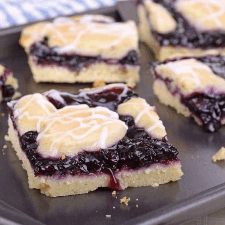 Air fryer blueberry pie bars with a golden crust and thick blueberry filling, sliced into squares on a plate.
