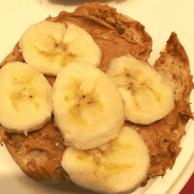 Toasted English muffin topped with peanut butter, banana slices, and crushed nuts.
