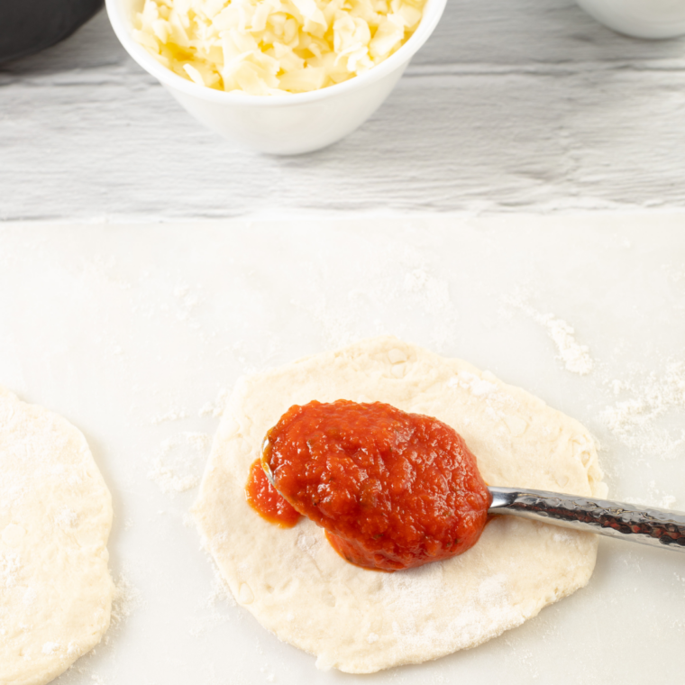 Flattened biscuit dough rounds pre-cooking in an air fryer basket