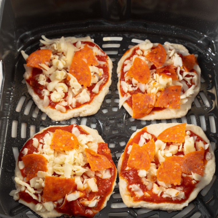 Finished air fryer biscuit pizzas with golden crusts and bubbling melted cheese