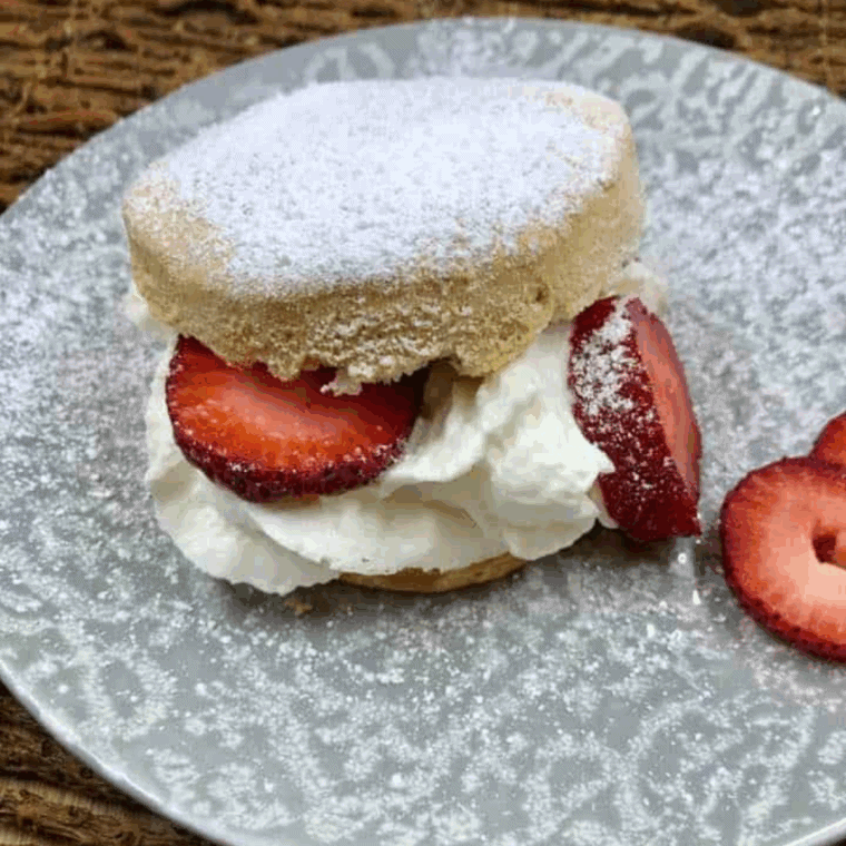 Air fryer biscuit strawberry shortcake topped with fresh strawberries and whipped cream.
