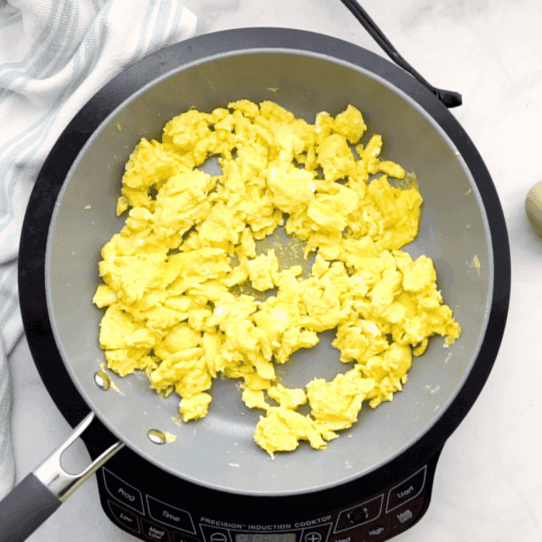 Cooking crumbled sausage and chopped bell peppers in a large black skillet over medium heat for the egg roll filling.
