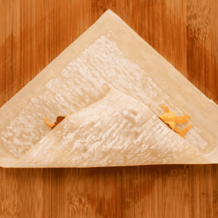 Wrapping the breakfast egg roll filling in an egg roll wrapper on a counter.