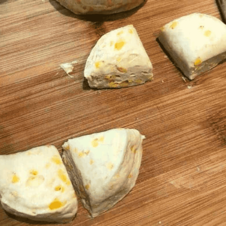 Cutting biscuit dough into pieces and rolling into balls for air fryer churro donut holes placed in greased basket.