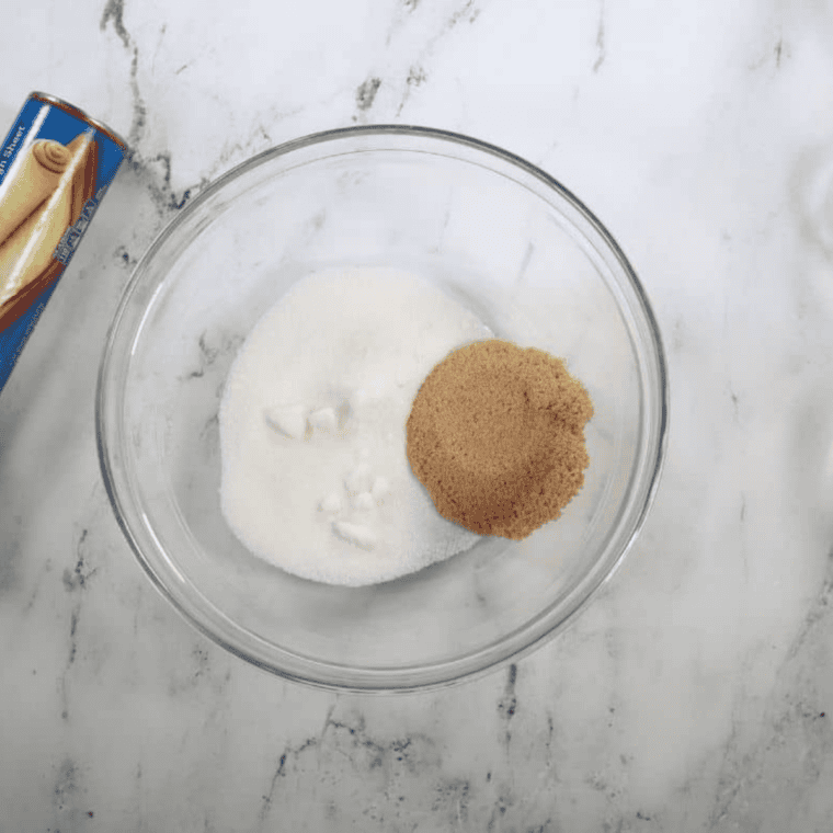 Melted butter in one bowl and a mixture of sugar and cinnamon in another bowl.