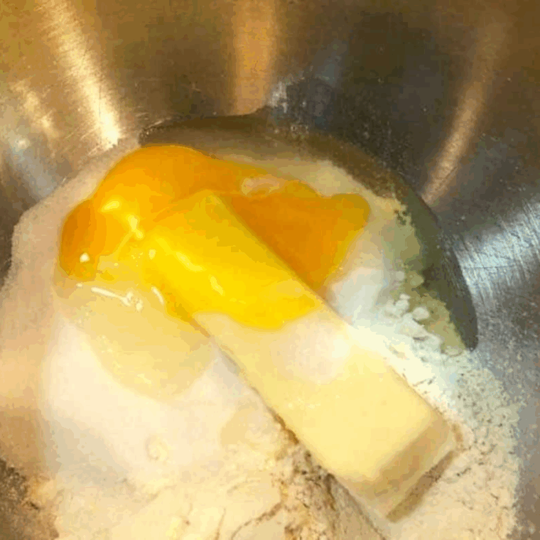 Mixing bowl with flour, baking soda, salt, sugar, butter, egg, vanilla, bananas, and Greek yogurt being combined for banana donut batter.