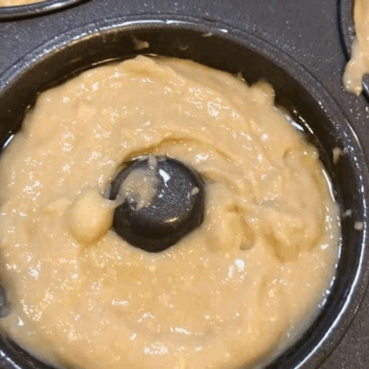 Donut molds sprayed with olive oil and filled with banana donut batter, ready for the air fryer.
