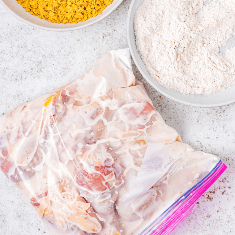 Crispy fried onions being crushed in a zip-top bag for the chicken coating